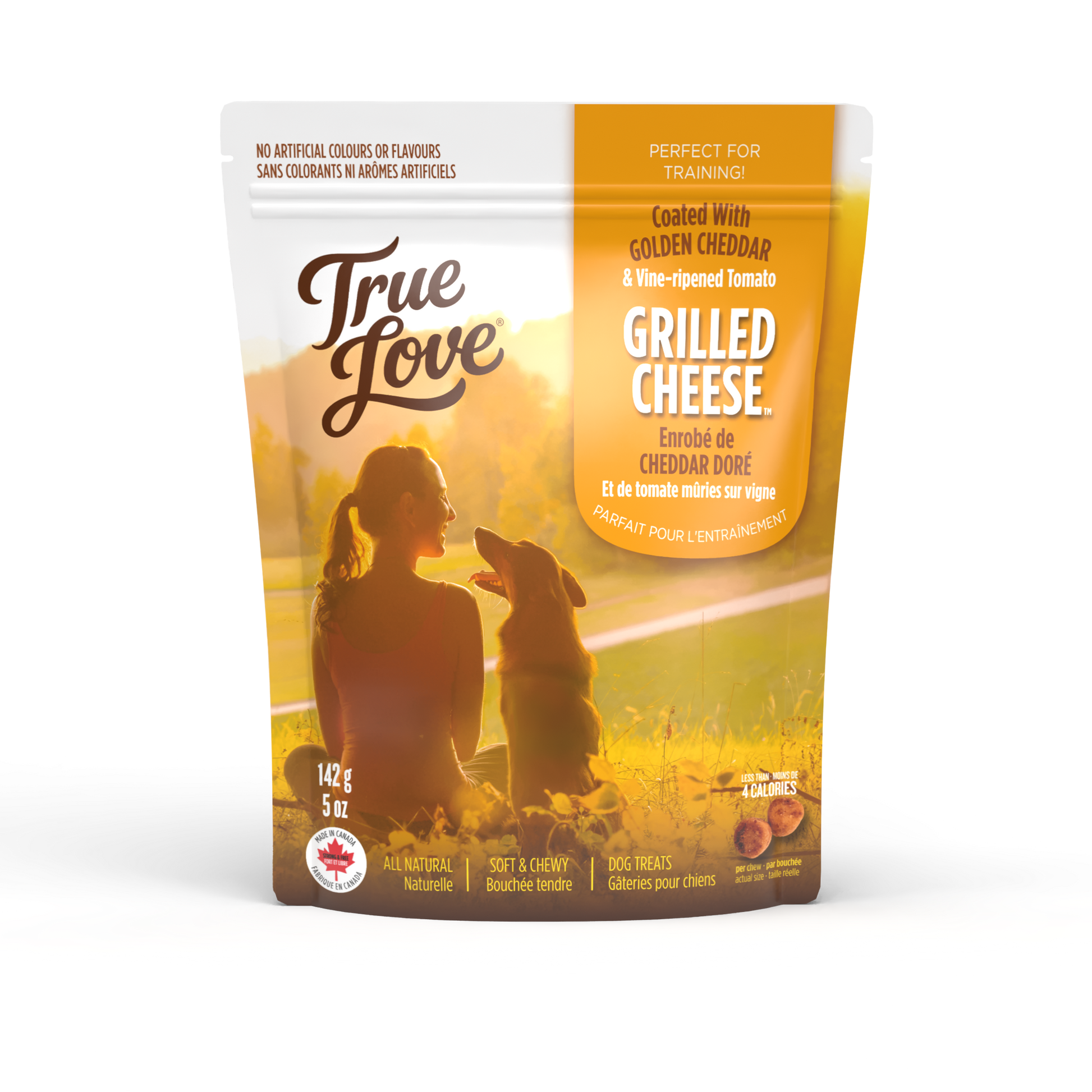 Bag of True Love dog treats with a woman smiling at her dog on the grass. Grilled Cheese flavour - golden cheddar and vine-ripened tomato.